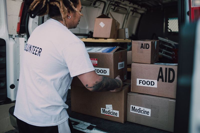 Volunteer moving food and medicine boxes from a van.