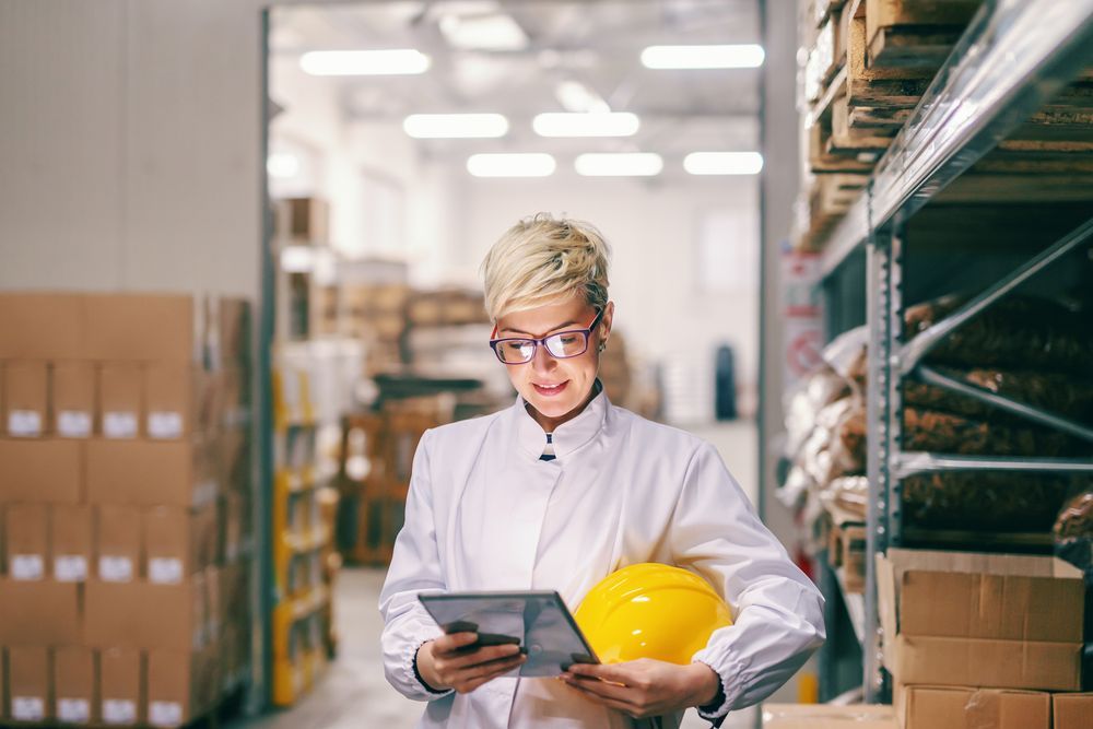A female manager in the warehouse using a tablet to check inventory