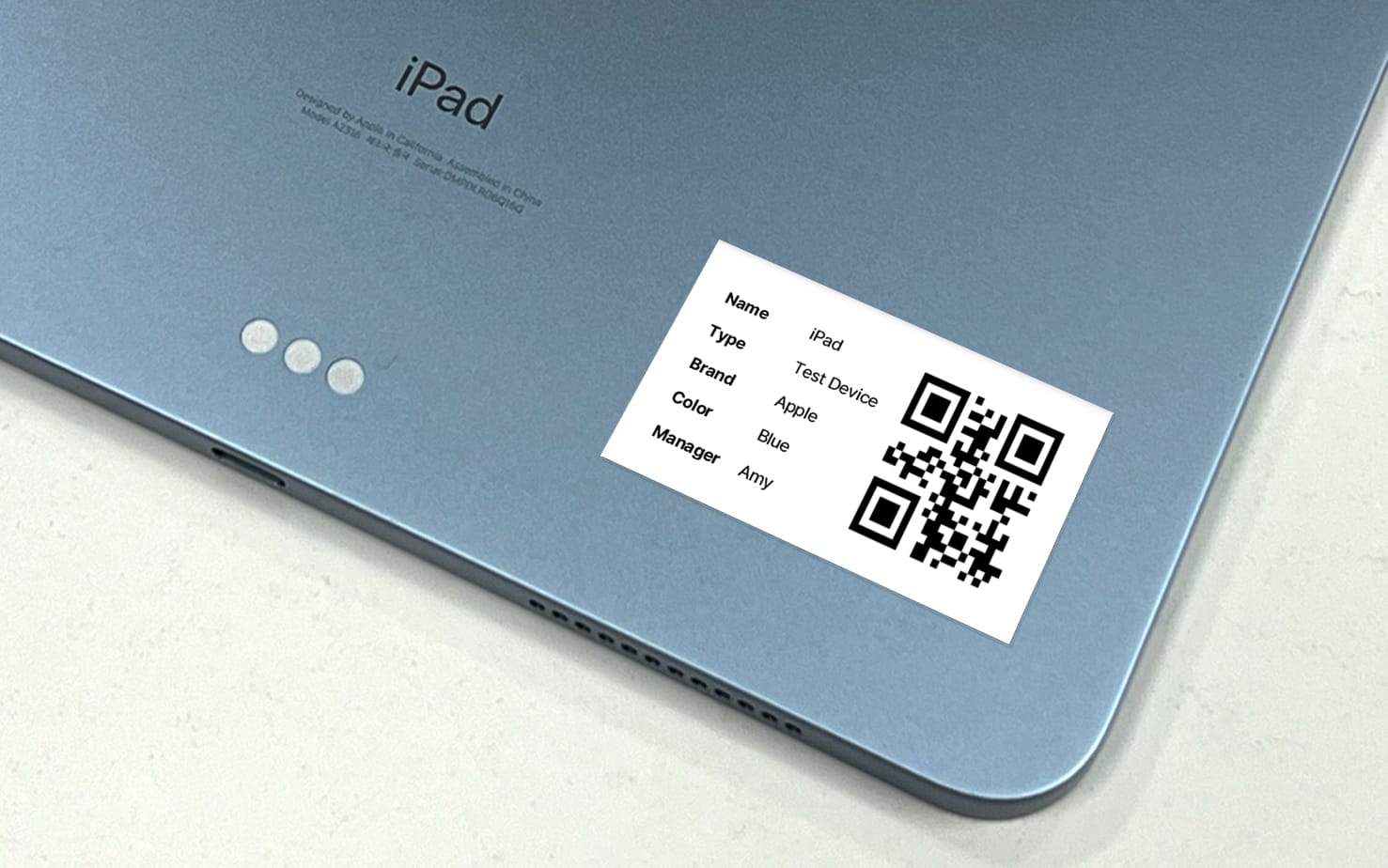 An iPad with a QR code label attached at its bottom right corner.