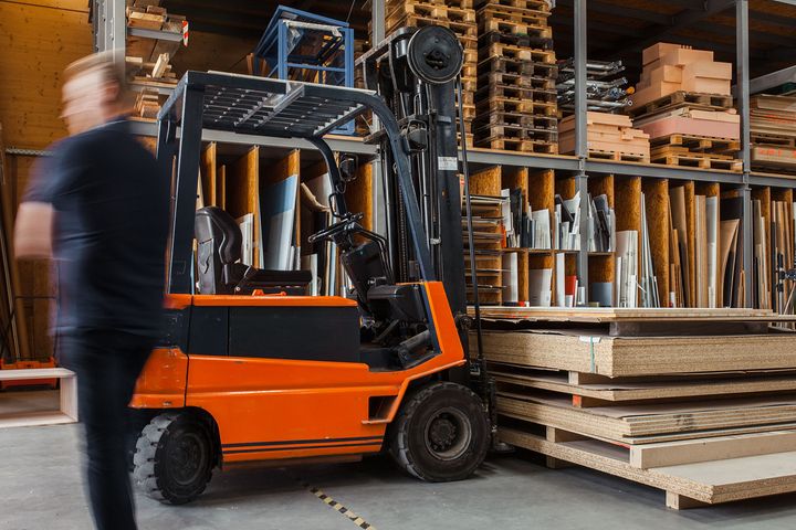 Forklift lifting pallets of plywood