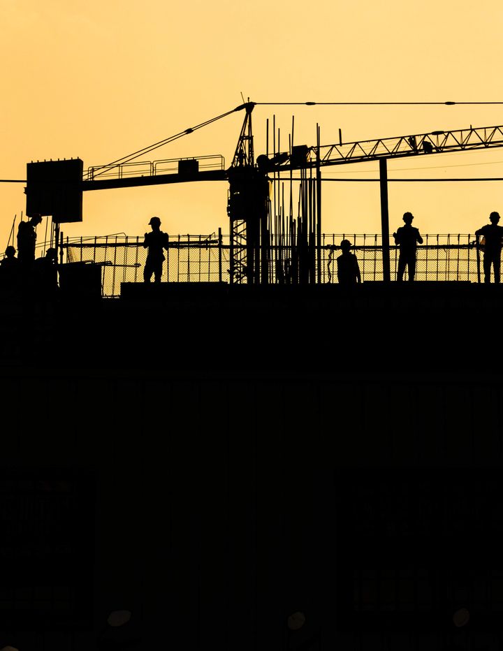Silhouette of working men in a construction site.