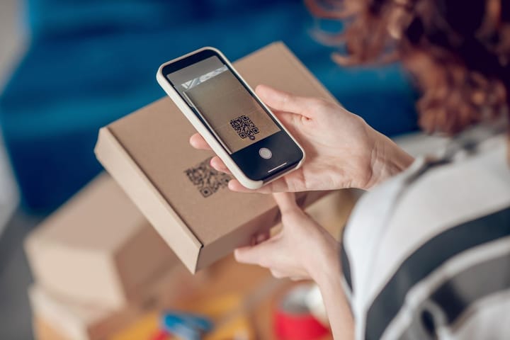 A person scanning a QR code on a box with their phone.