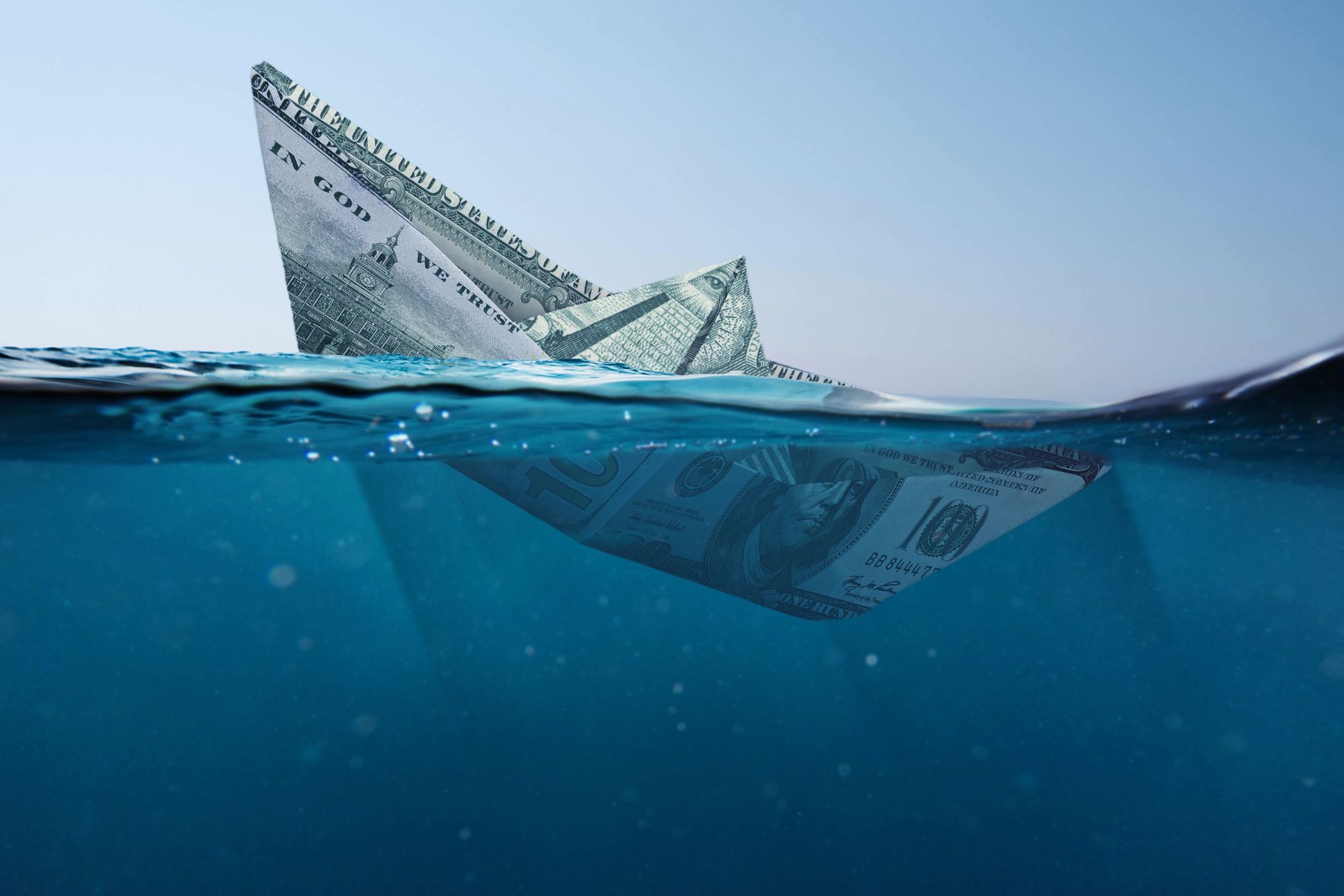 바다에 가라앉고 있는 달러로 접은 배.